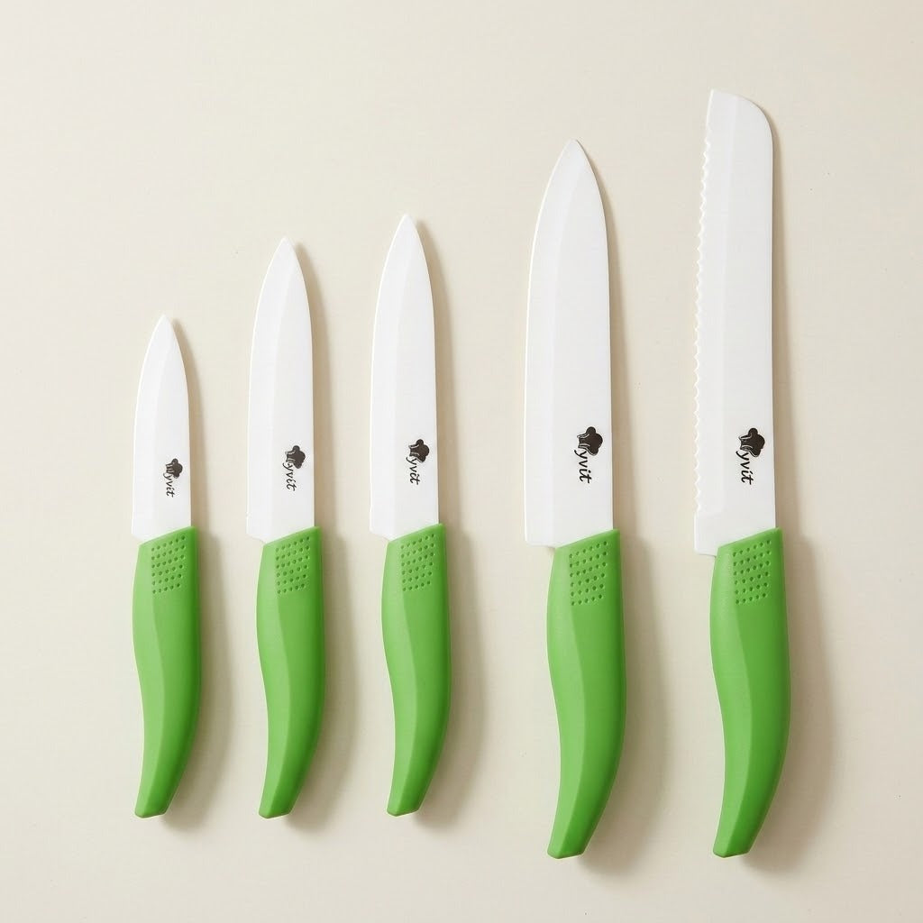 Five white-bladed knives with green handles, including one serrated knife, are arranged vertically by size on a cream background.