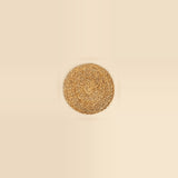 A round woven natural fiber placemat in a light tan color, centered on a solid cream background.