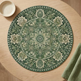 A round green and beige mandala-patterned placemat on a light wood table, styled with a small white bowl and a folded green napkin.