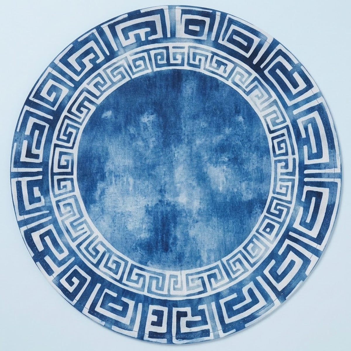 A round decorative plate or tray featuring a blue and white Greek key pattern border with a textured blue center, shown against a light blue background.