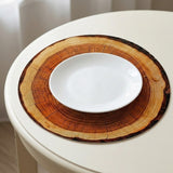 A white plate sits on a round brown wood-slice print placemat on a white table.