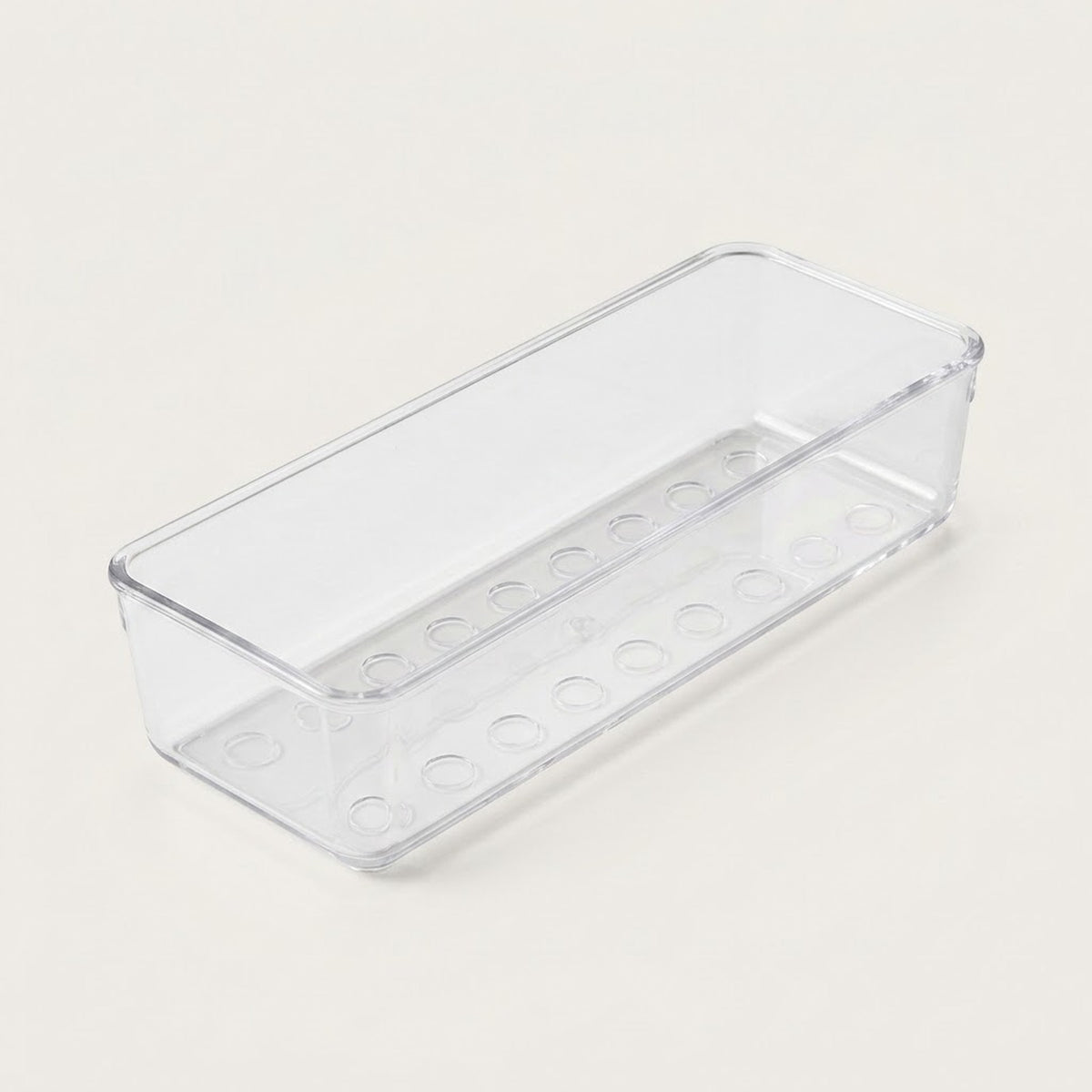 Long clear rectangular organizer tray with circular base details and rounded corners rests diagonally on an off-white background.