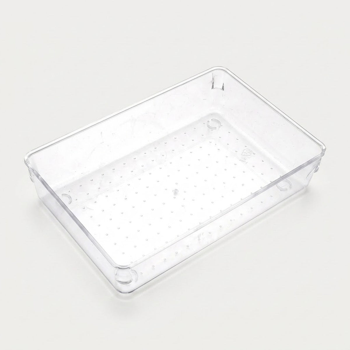Wide clear rectangular organizer tray with a dotted base, smooth sides, and rounded corners sits on an off-white background.