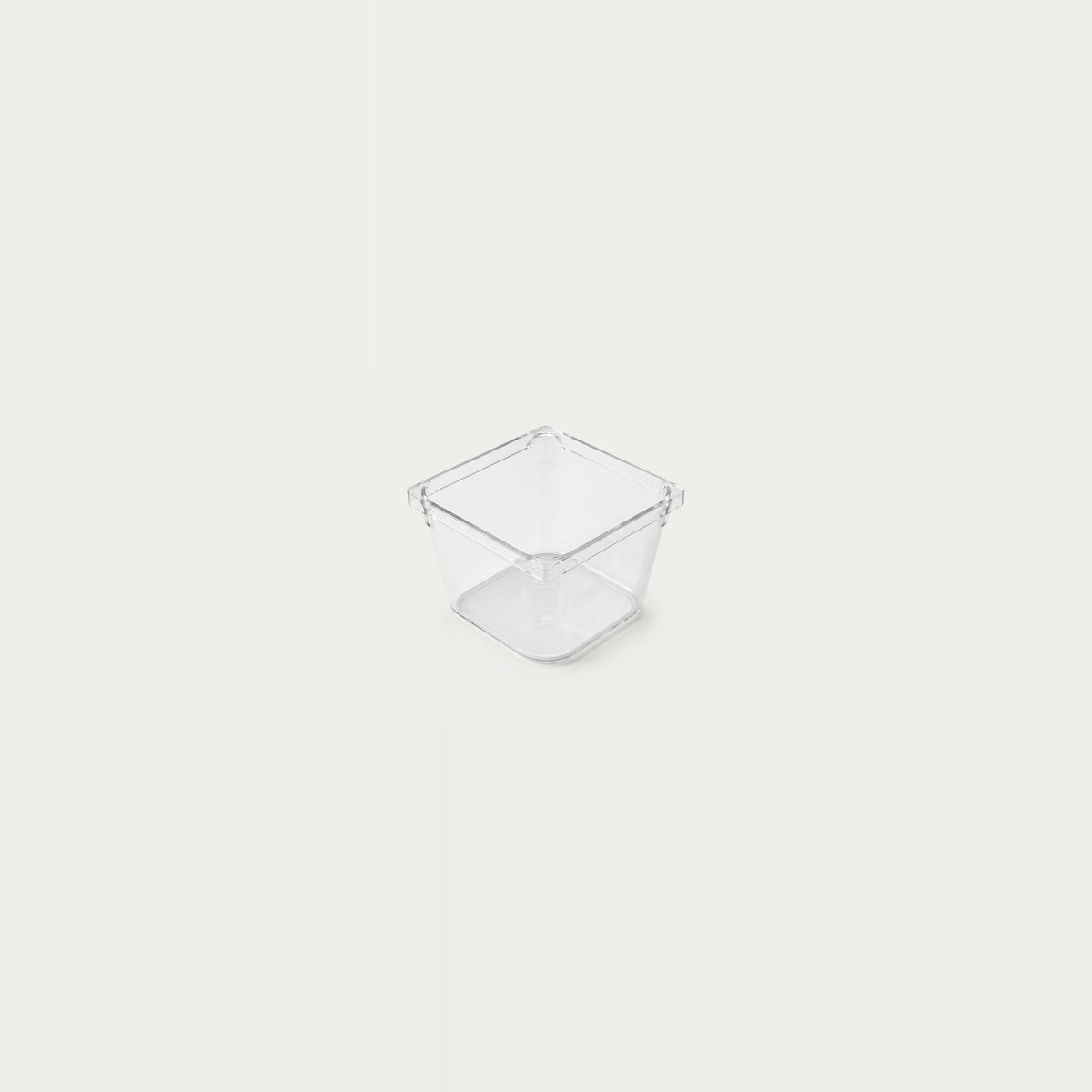 A small empty clear square organizer with smooth sides sits centered against an off-white background.