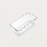 An empty clear rectangular organizer with smooth sides and rounded corners sits diagonally against an off-white background.