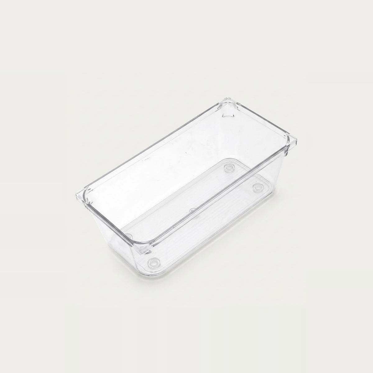 An empty clear rectangular organizer with smooth sides and rounded corners sits diagonally against an off-white background.