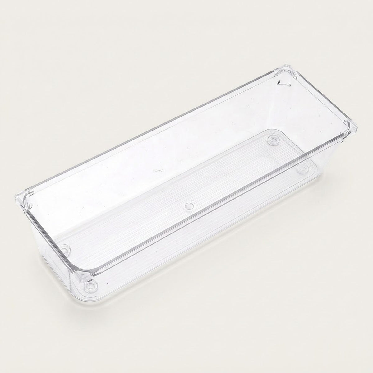 An empty long clear rectangular organizer with smooth sides and rounded corners sits diagonally against an off-white background.