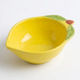A yellow ceramic bowl designed to look like a lemon, featuring green leaf details on one side and a small brown stem, shown on a plain white background.