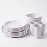 A minimalist white ceramic dinnerware set including plates, bowls, and cups, arranged neatly on a clean white background.