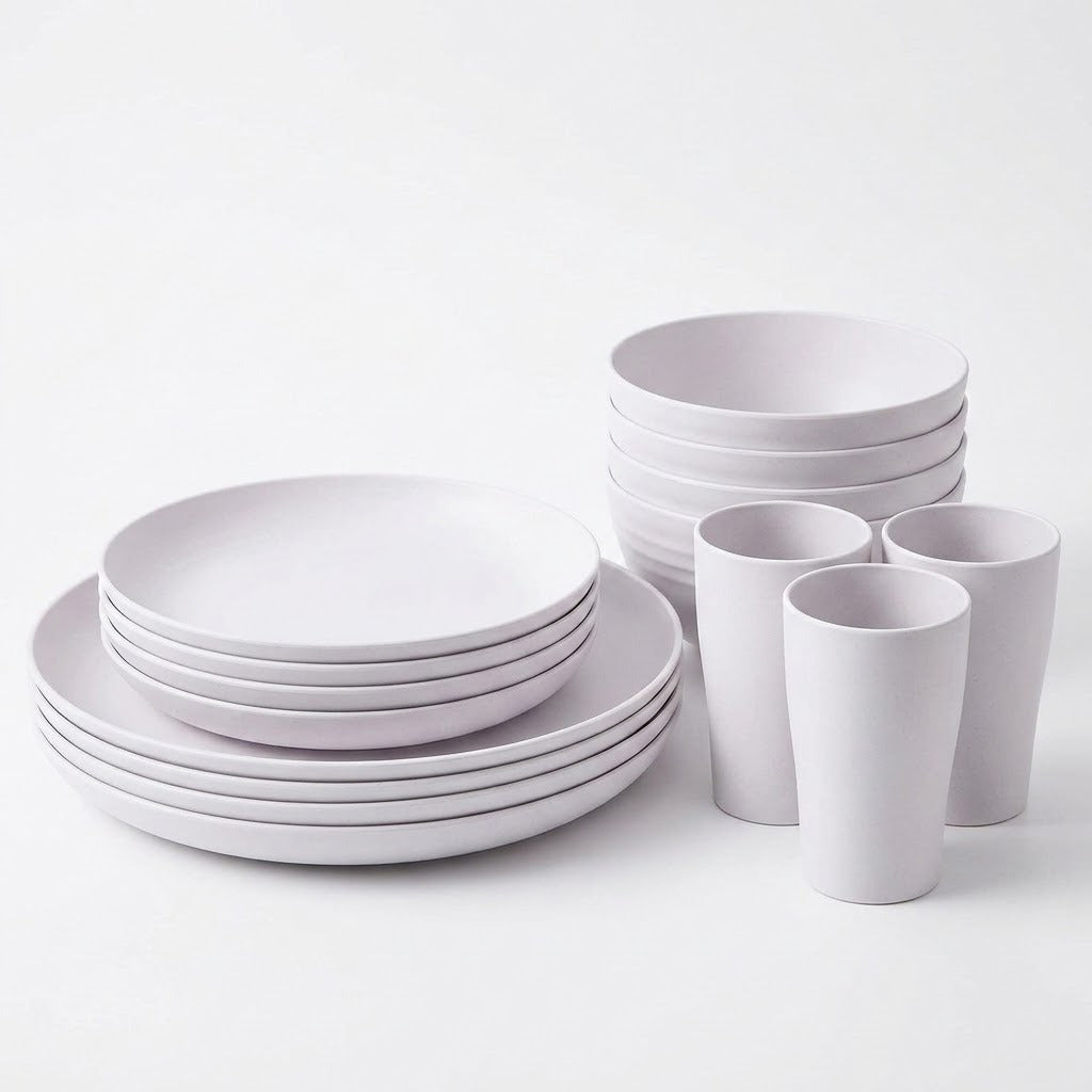 A minimalist white ceramic dinnerware set including plates, bowls, and cups, arranged neatly on a clean white background.