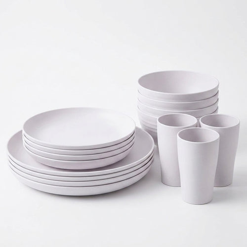 A minimalist white ceramic dinnerware set including plates, bowls, and cups, arranged neatly on a clean white background.