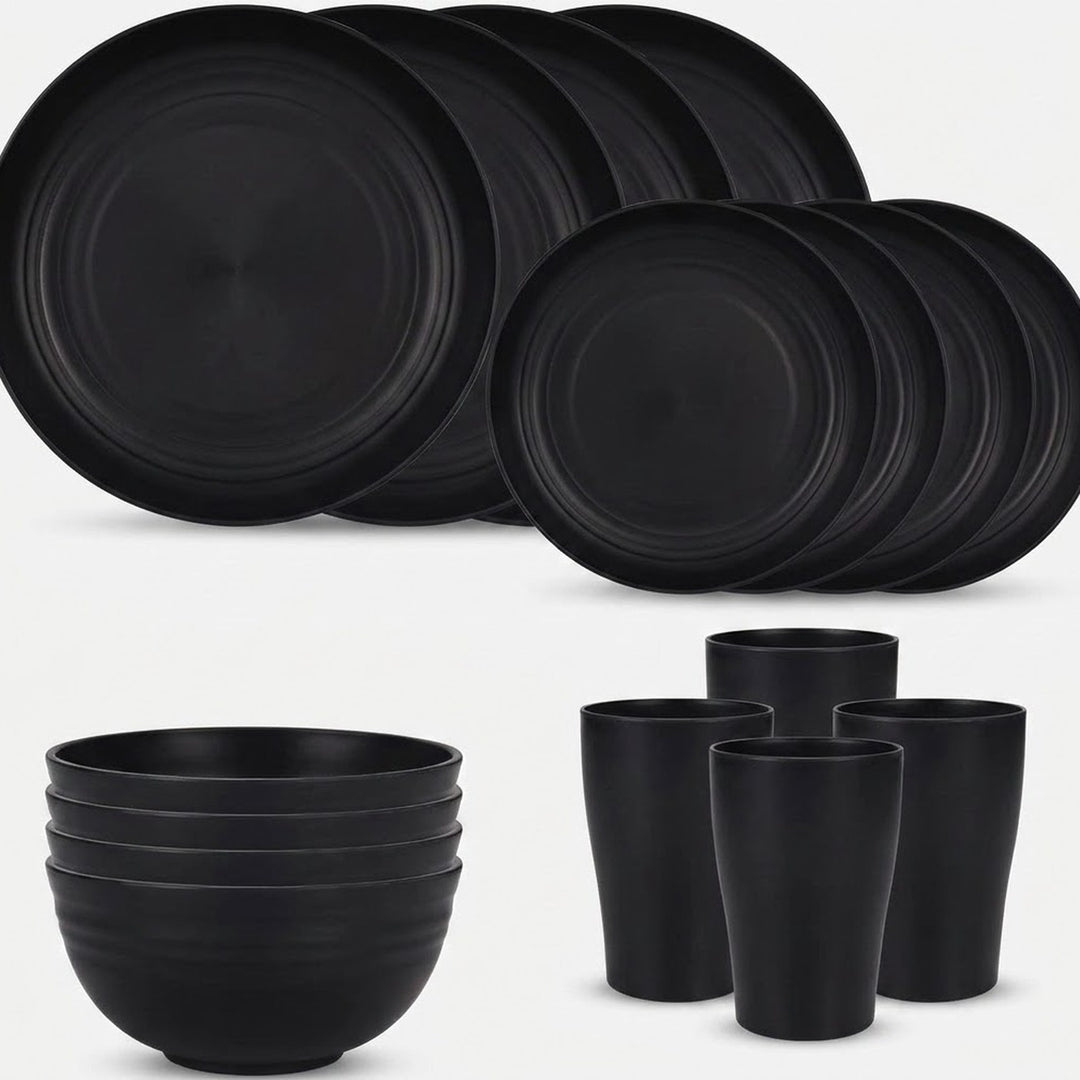 Black dinnerware is arranged against a white background with overlapping large and small plates, four stacked bowls, and four tall cups.