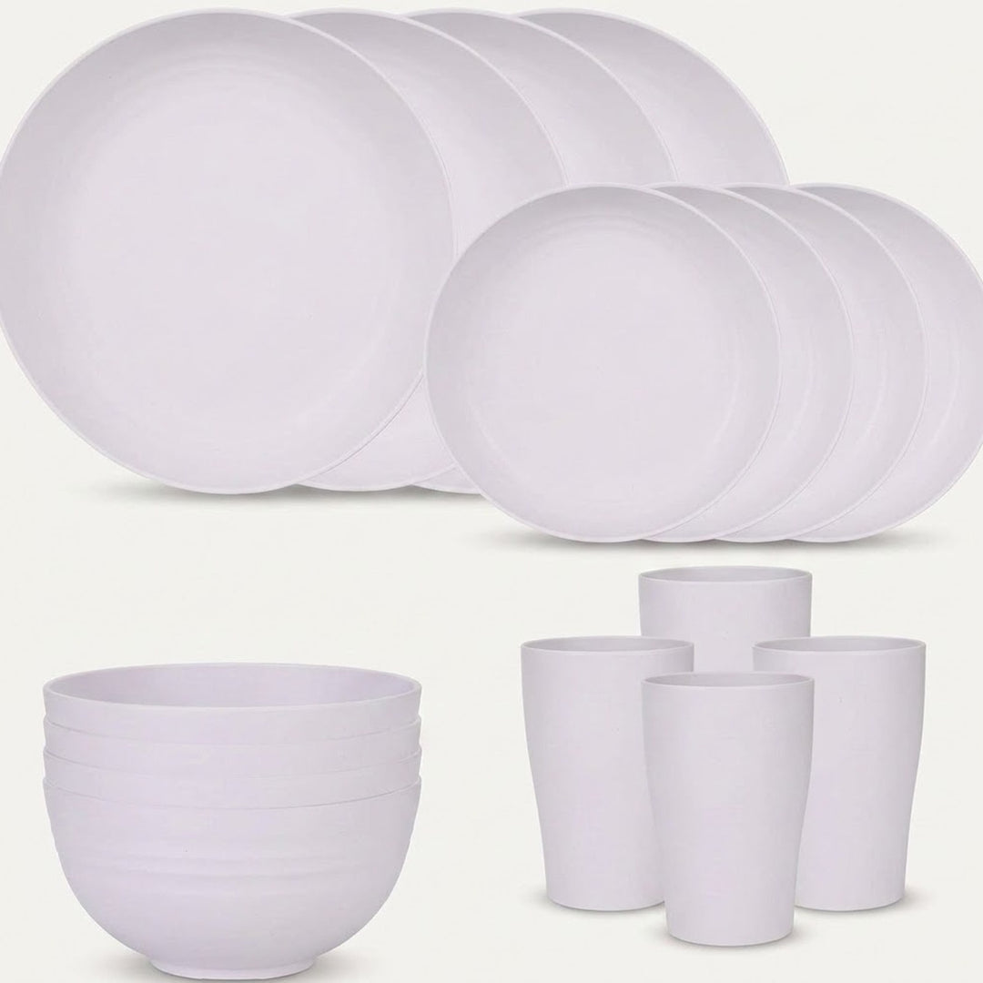 White dinnerware is arranged against a pale background with overlapping large and small plates, stacked bowls, and four tall cups.