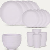 White dinnerware is arranged against a pale background with overlapping large and small plates, stacked bowls, and four tall cups.