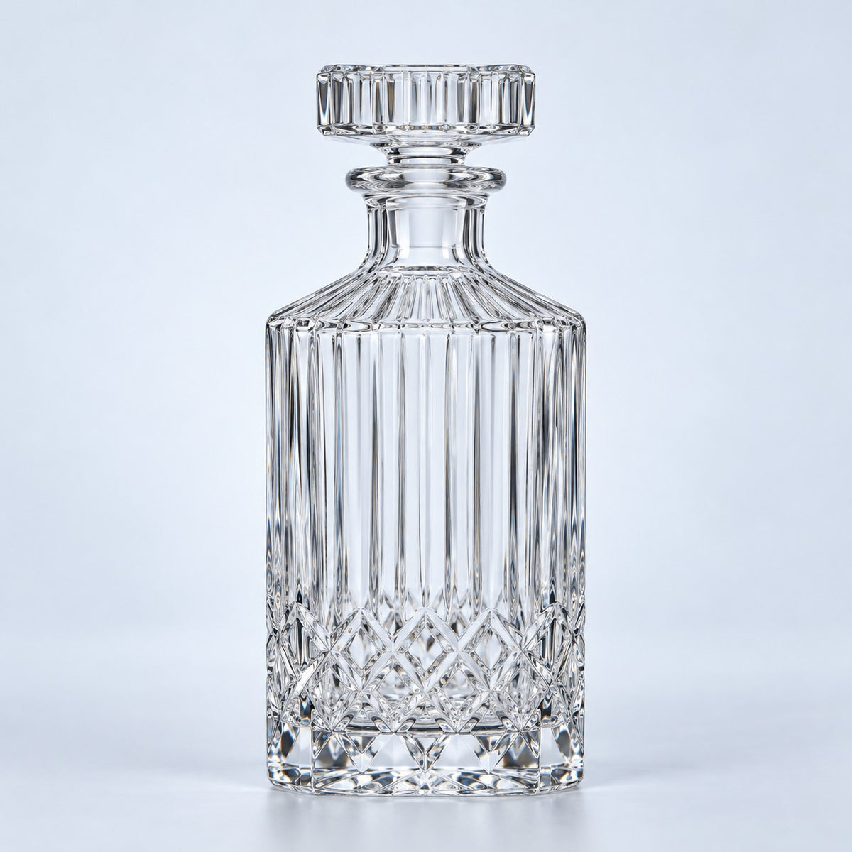 The clear fluted diamond glass decanter with its matching stopper stands against a pale blue backdrop.