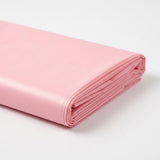 Close-up of a folded pink plastic tablecloth showing layered edges on a white background.