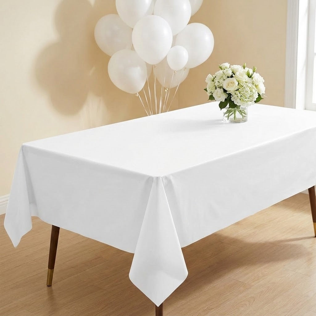 A square white fabric sheet or napkin laid flat on a light wood surface, with a yellow tape measure along the left and bottom edges to indicate size.