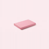 A folded pink sheet or fabric item shown on a plain pale pink background.