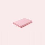 A folded light pink fabric item, likely a sheet or blanket, shown on a solid pale pink background.