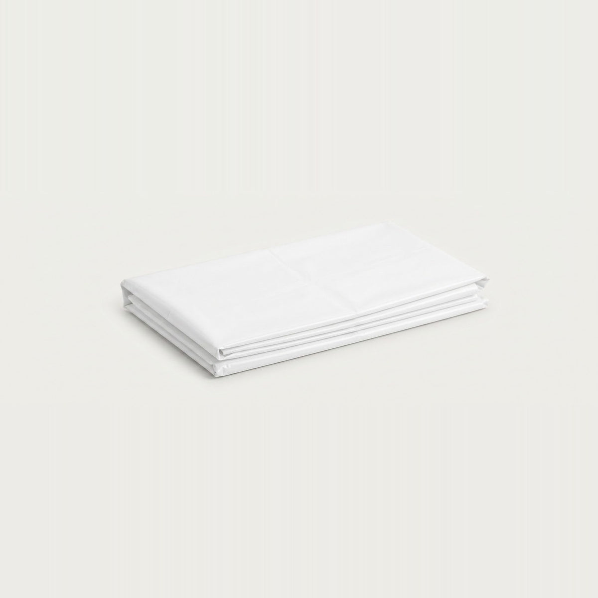 A neatly folded stack of white fabric sheets or a bedding set, photographed on a clean, solid, very light off-white background.
