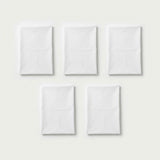Five folded white plastic tablecloths are arranged in two rows on a light background.