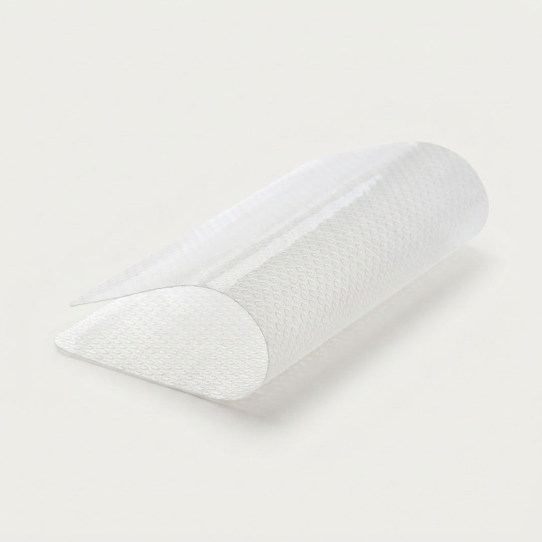 A white textured semi-transparent arch support pillow, shown partially rolled on a clean off-white background.