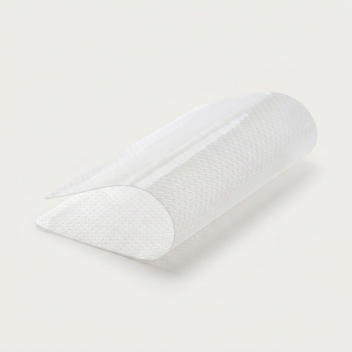 A white textured semi-transparent arch support pillow, shown partially rolled on a clean off-white background.