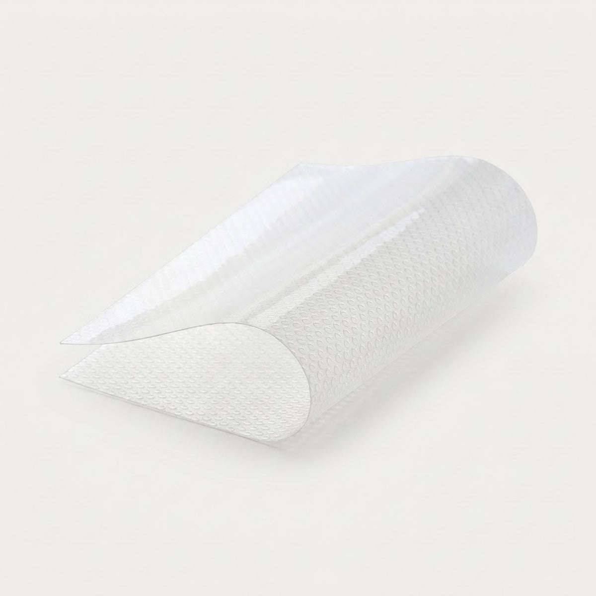 A translucent white textured silicone or plastic wedge-shaped insert, shown partially rolled on a clean off-white background.