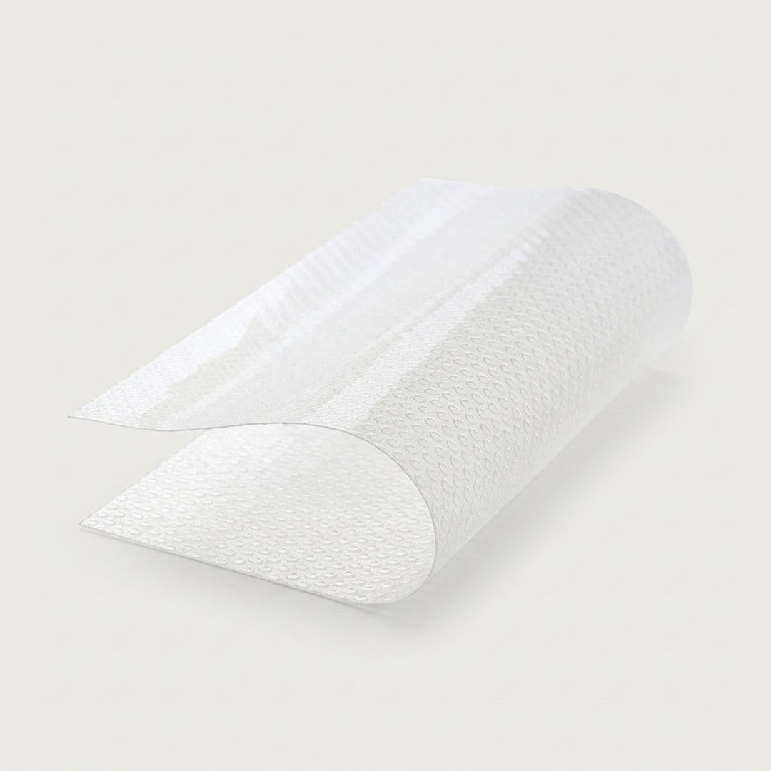 A roll of textured white adhesive tape, partially unrolled to show its patterned surface, set against a solid light gray background.