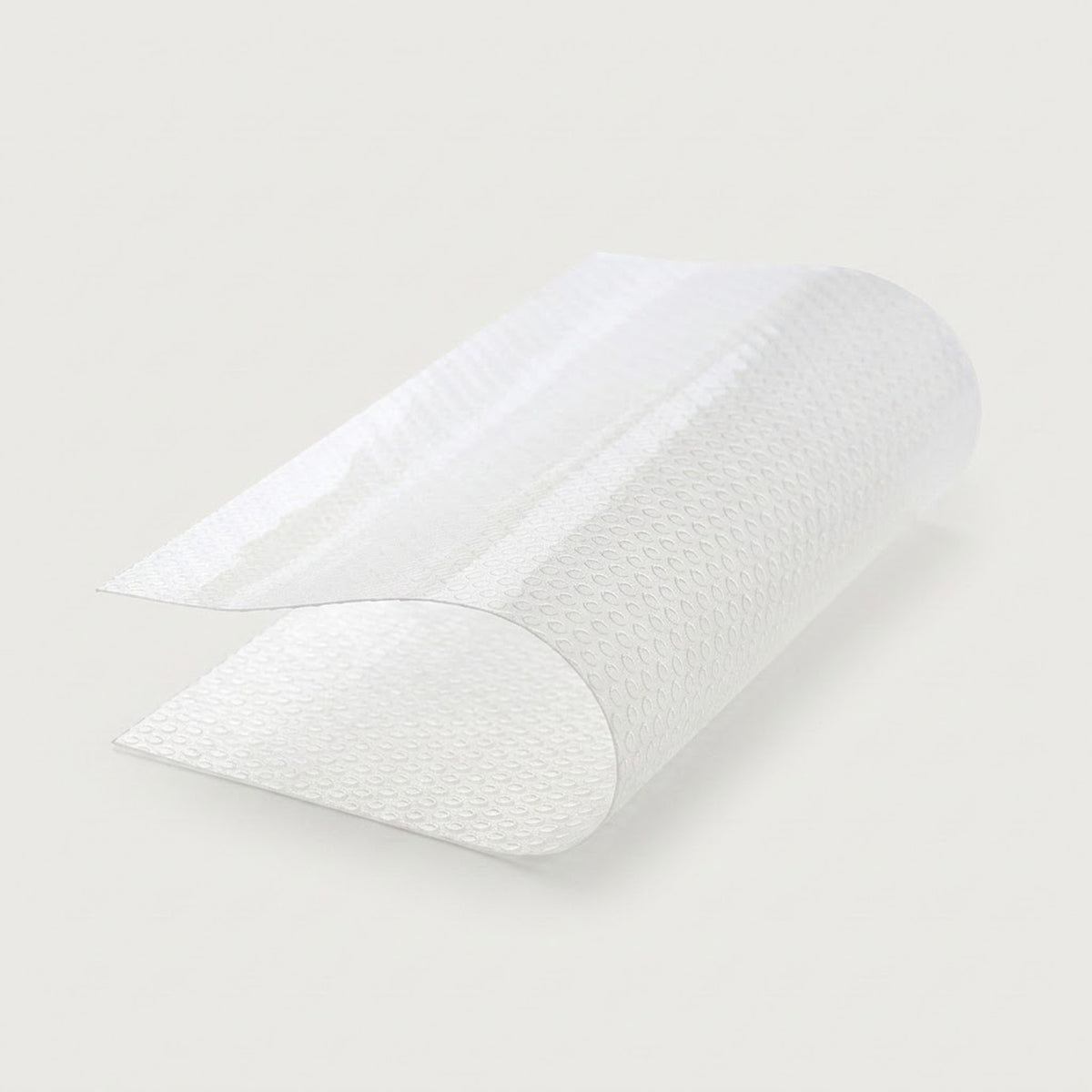 A roll of textured white adhesive tape, partially unrolled to show its patterned surface, set against a solid light gray background.