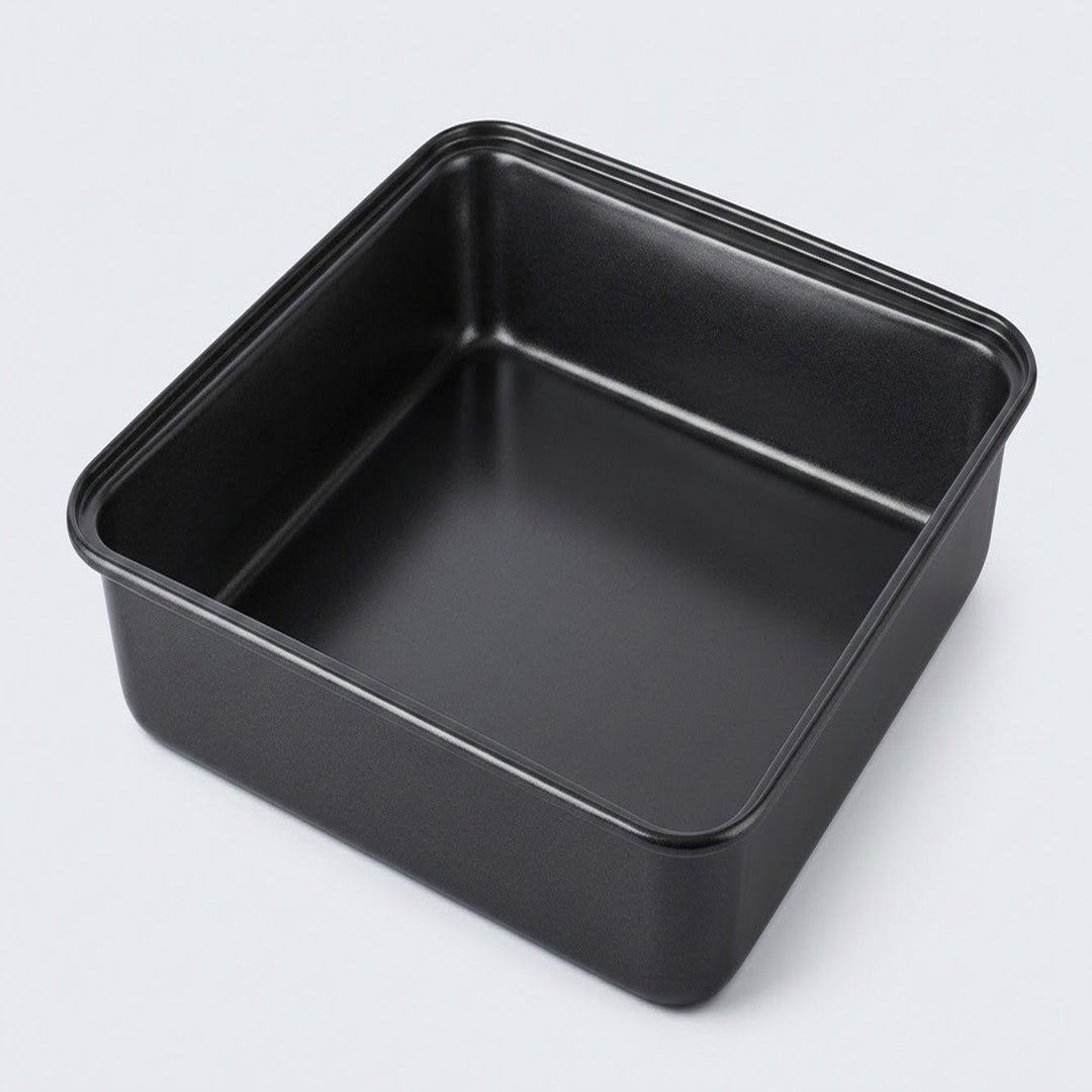 A square black non-stick baking pan with raised rim edges, photographed from an elevated angle on a light gray background.