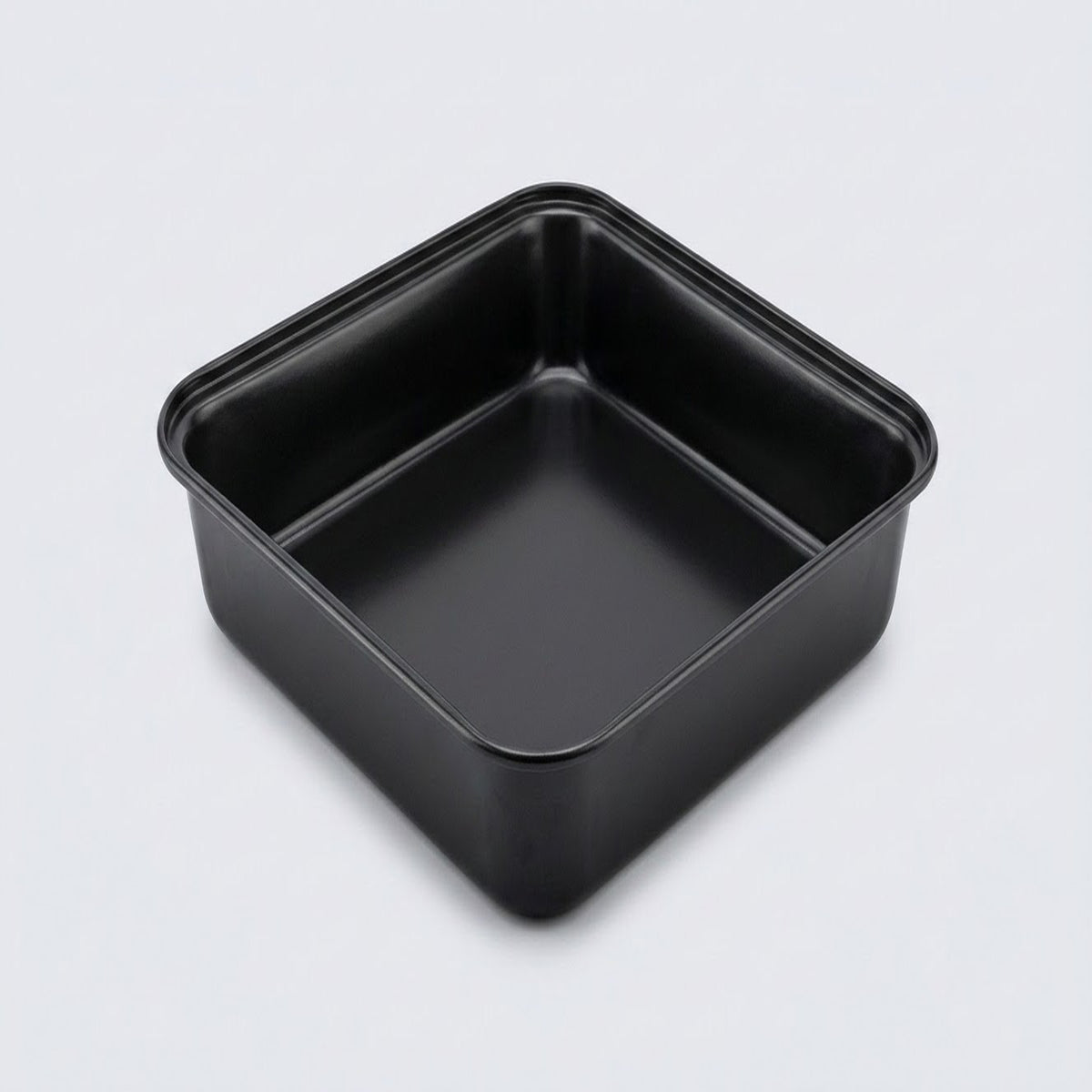A square black non-stick baking pan with a raised rim and a single center divider, shown from an elevated perspective on a light gray background.