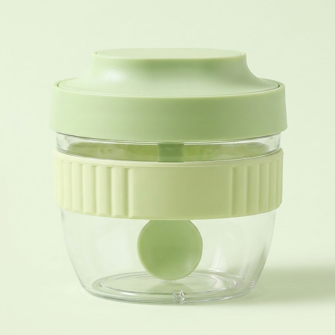 A small clear plastic food chopper jar with a light green lid and a pale yellow-green ribbed handle band, shown on a light green background.