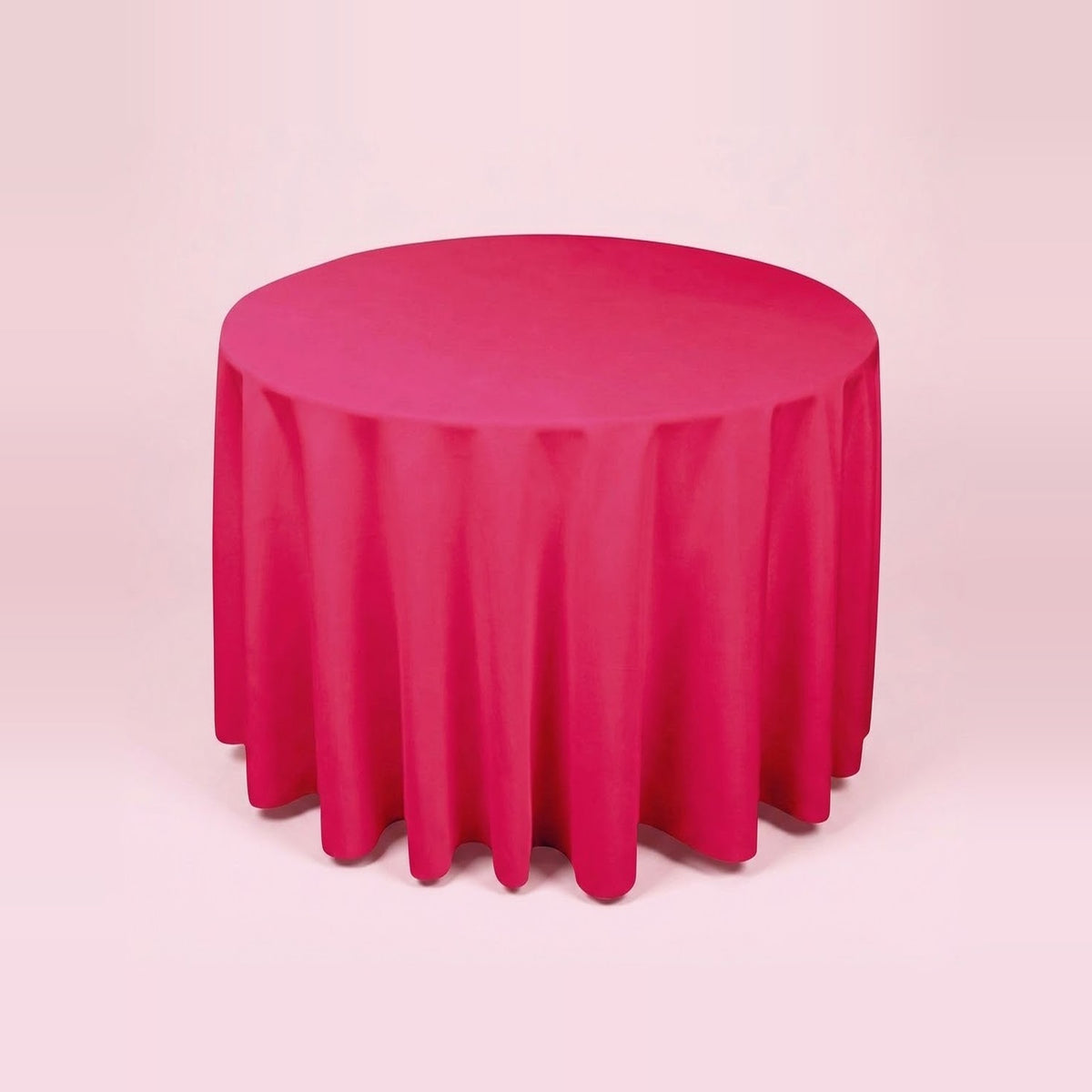 A round table covered with a bright pink tablecloth, shown against a solid pale pink background.