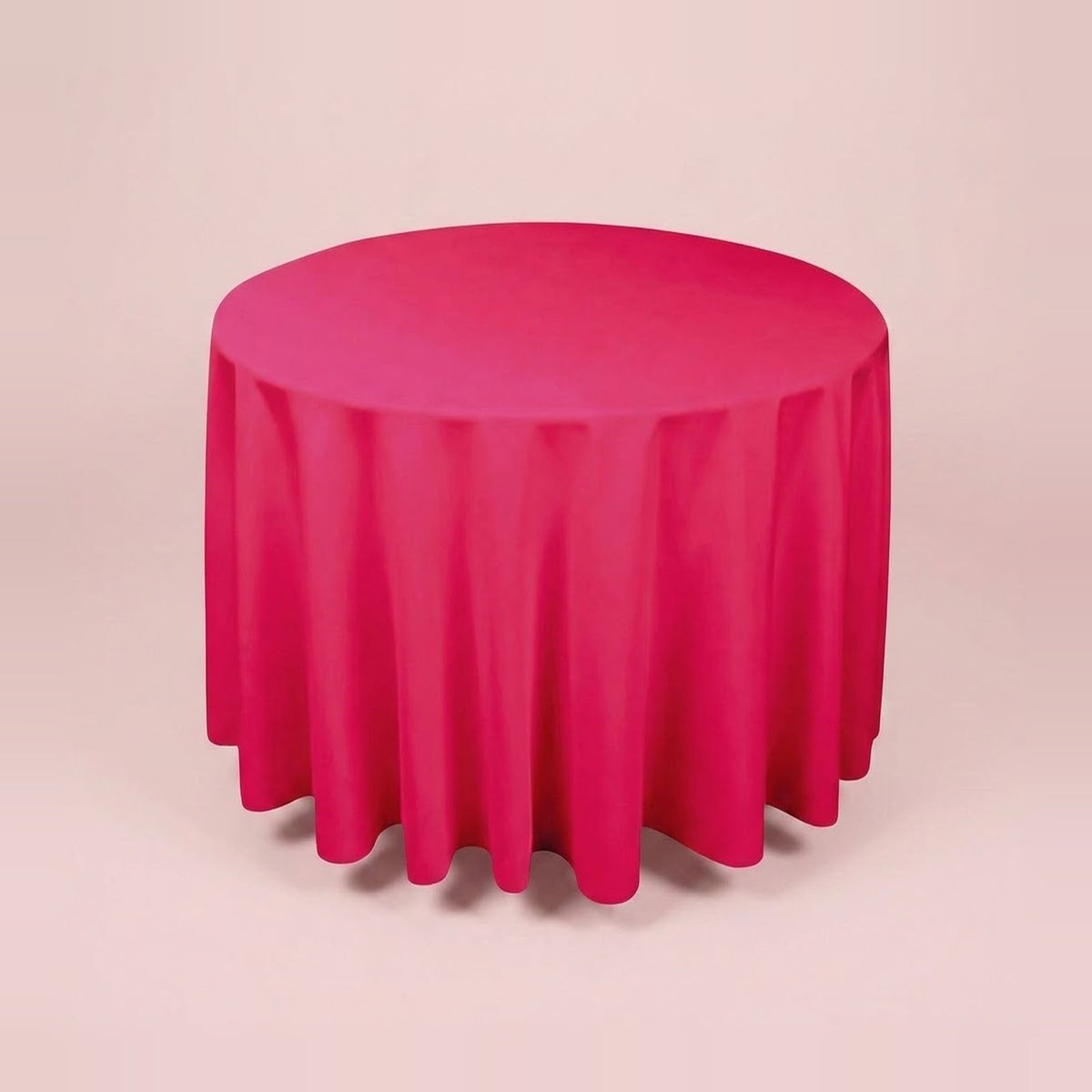 A round table covered with a bright pink tablecloth, shown against a plain light beige studio background.