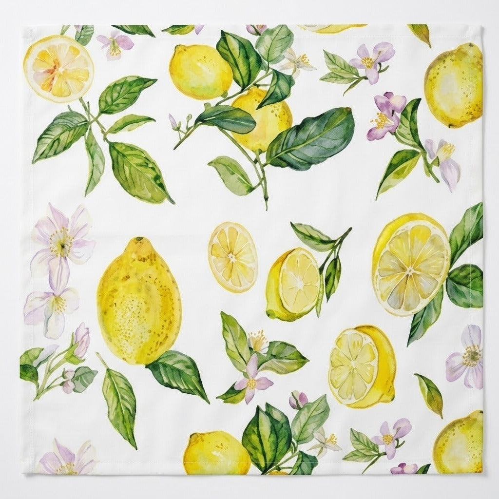 A square white fabric napkin or kitchen towel featuring a watercolor-style print of lemons, lemon slices, green leaves, and small light purple flowers, shown flat against a white background.