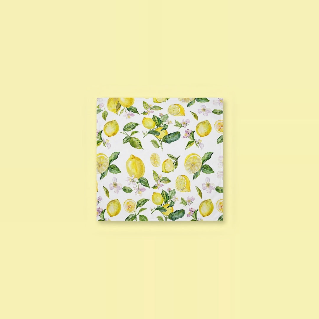 A square white napkin featuring a watercolor-style lemon and leaf pattern, centered on a pale yellow background.
