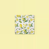 A square white napkin featuring a watercolor-style lemon and leaf pattern, centered on a pale yellow background.