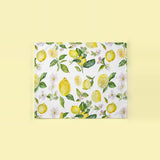 A square canvas print featuring a watercolor lemon and floral pattern on a white background, displayed against a solid pale yellow backdrop.