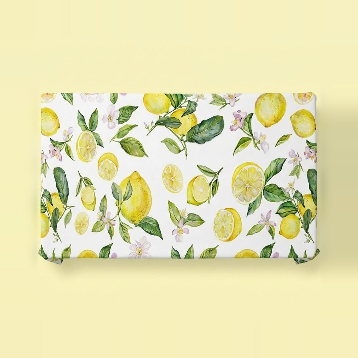 A rectangular gift wrap or fabric panel featuring a watercolor lemon and leaf pattern on a white background, displayed flat against a pale yellow backdrop.
