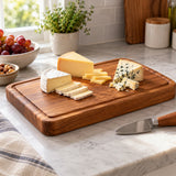 Wooden Kitchen Cutting Board holds sliced cheese on a kitchen counter beside a cheese knife.