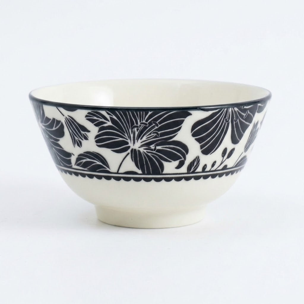 A ceramic bowl with a glossy white glaze and a navy blue floral pattern around the upper exterior, shown on a clean white background.