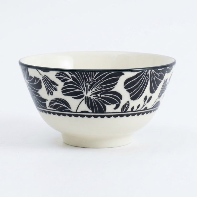 A ceramic bowl with a glossy white glaze and a navy blue floral pattern around the upper exterior, shown on a clean white background.