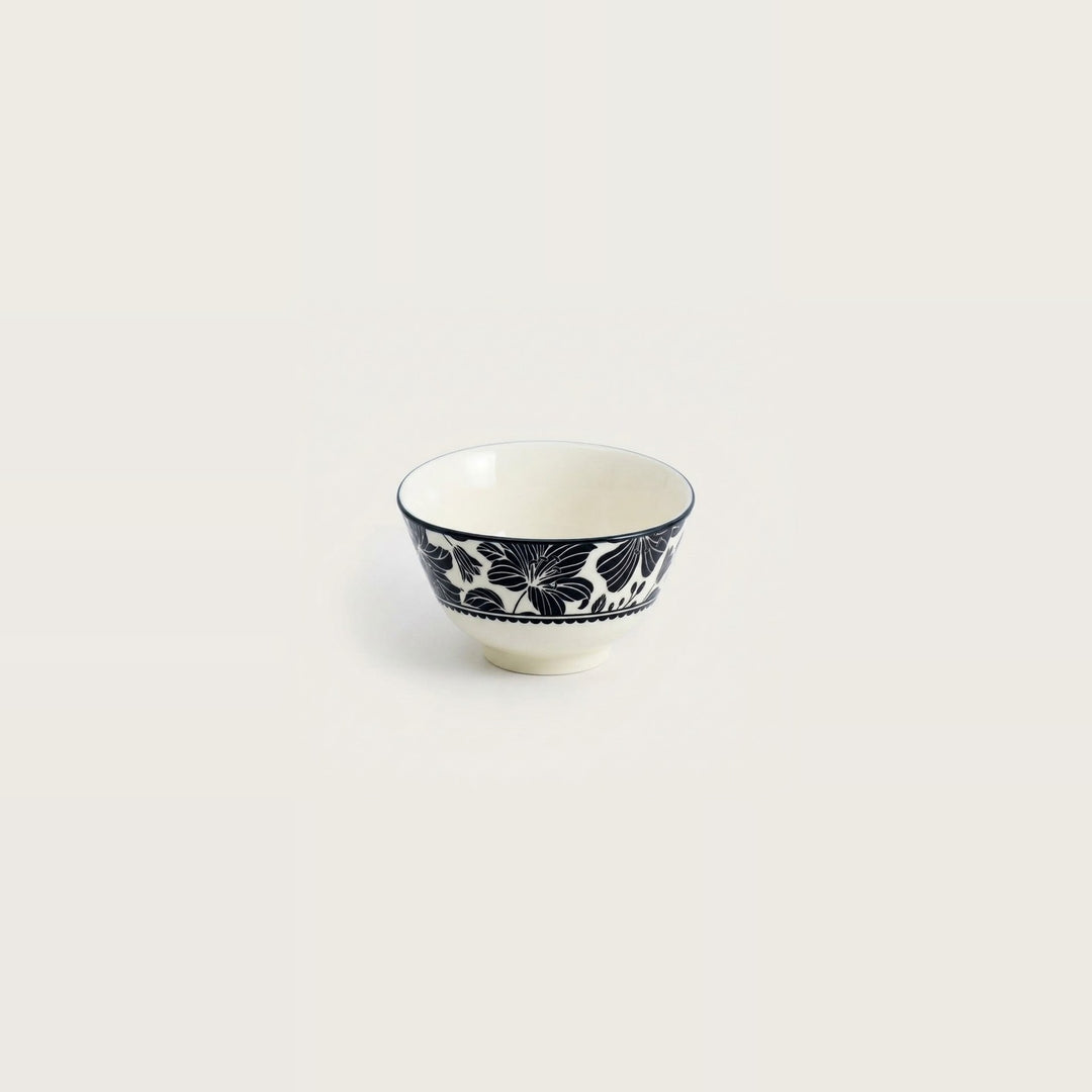 A small white ceramic bowl with a navy blue floral pattern around the outer side, shown against a solid off-white background.