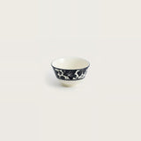 A small white ceramic bowl with a navy blue floral pattern around the outer side, shown against a solid off-white background.