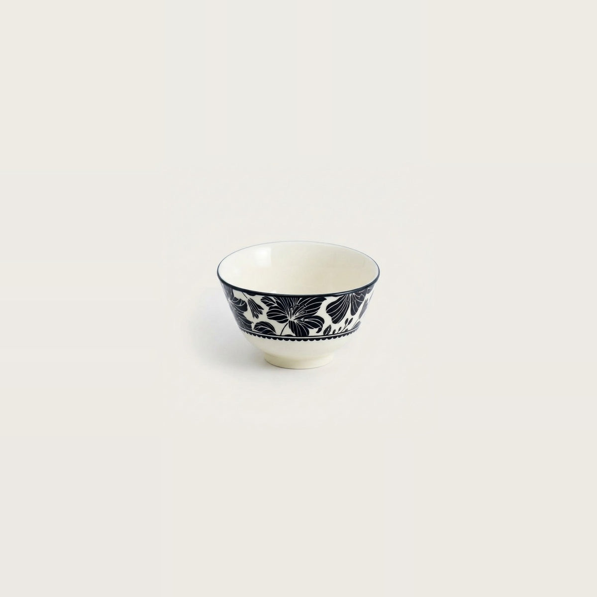 A small white ceramic bowl with a navy blue floral pattern around the outer side, shown against a solid off-white background.