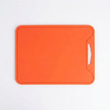 An orange rectangular cutting board with rounded corners and a handle cutout on the right side, shown from a top-down view on a white background.