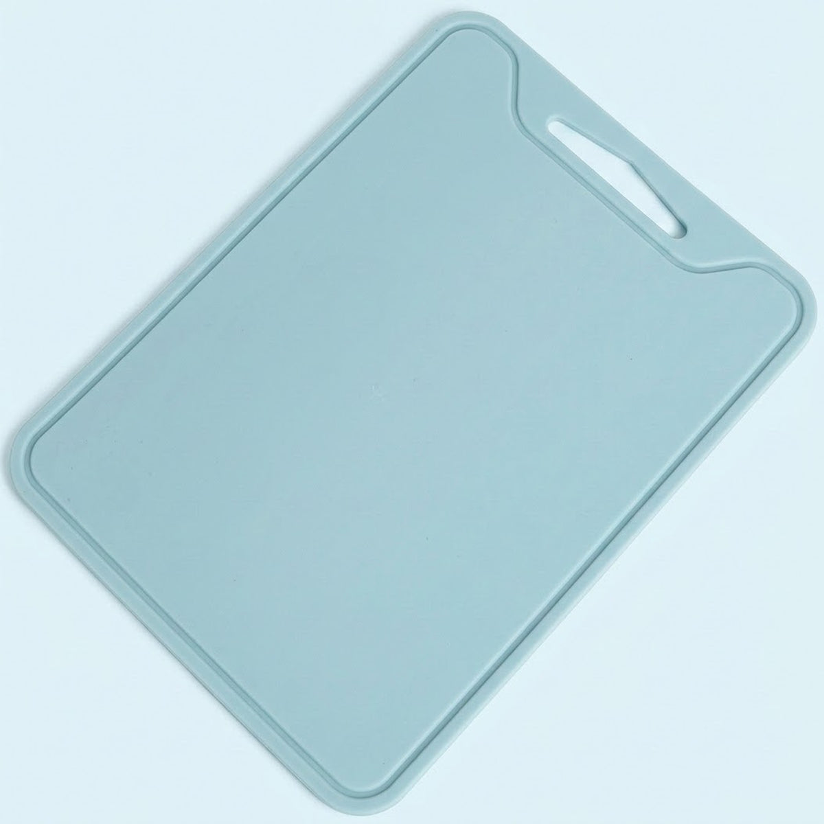 A light blue rectangular cutting board with rounded corners and a built-in handle cutout in the top right corner, shown on a matching light blue background.