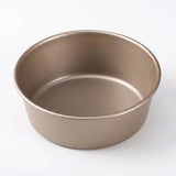A round, shallow metal baking pan with a matte taupe finish, photographed from a high angle on a clean white background.