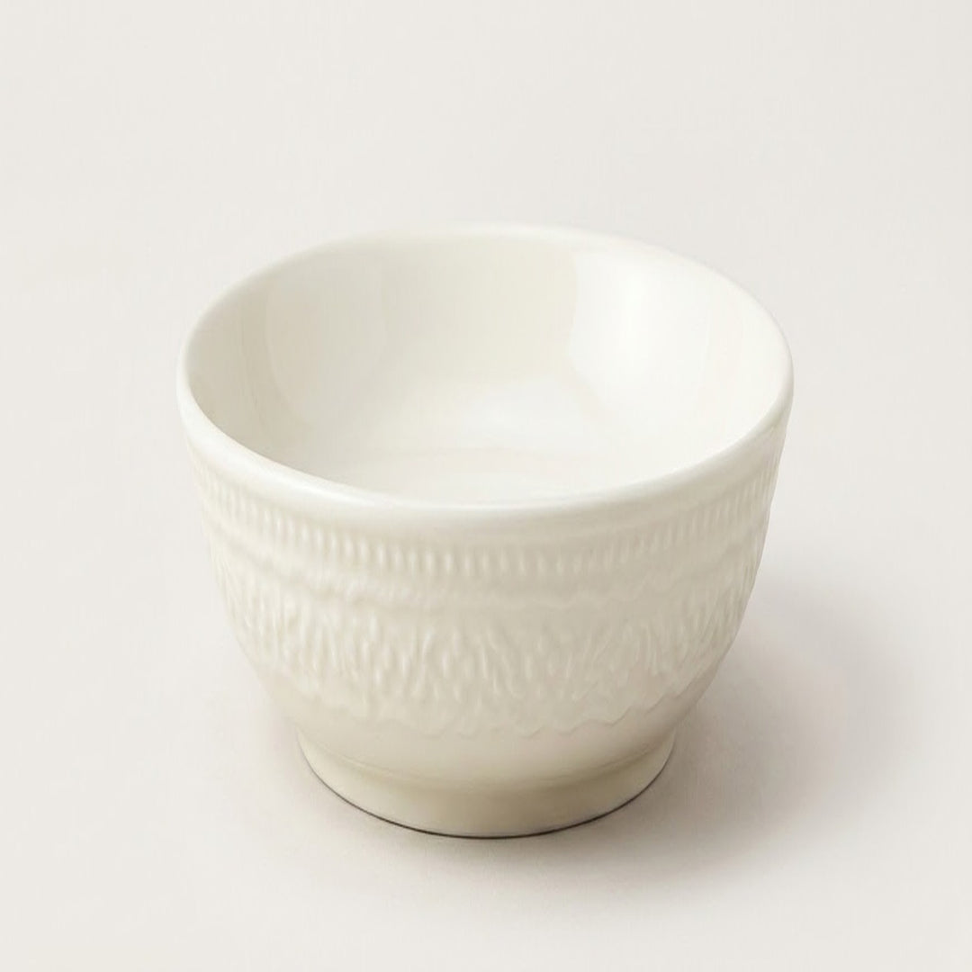 A small white ceramic bowl with a textured, embossed pattern on the exterior, shown on a clean, light off-white background.